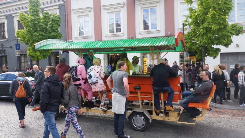 Människor på och runtom en cyklande bar med cirka tio platser