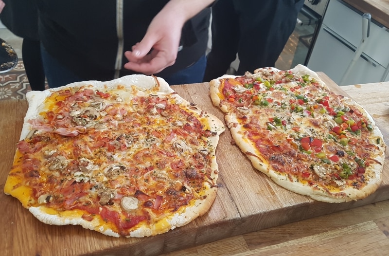 Två pizzor på tjock skärbräda i trä