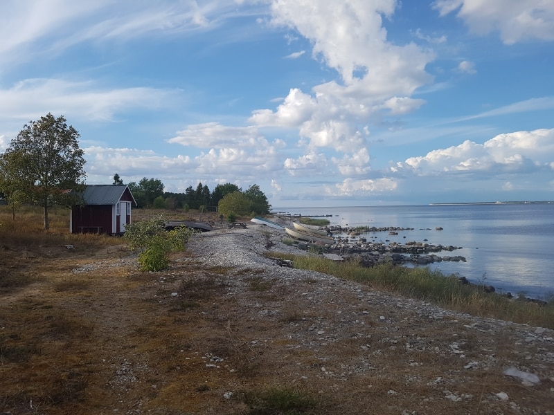 Ett litet rött hus på en stenstrand vid havet