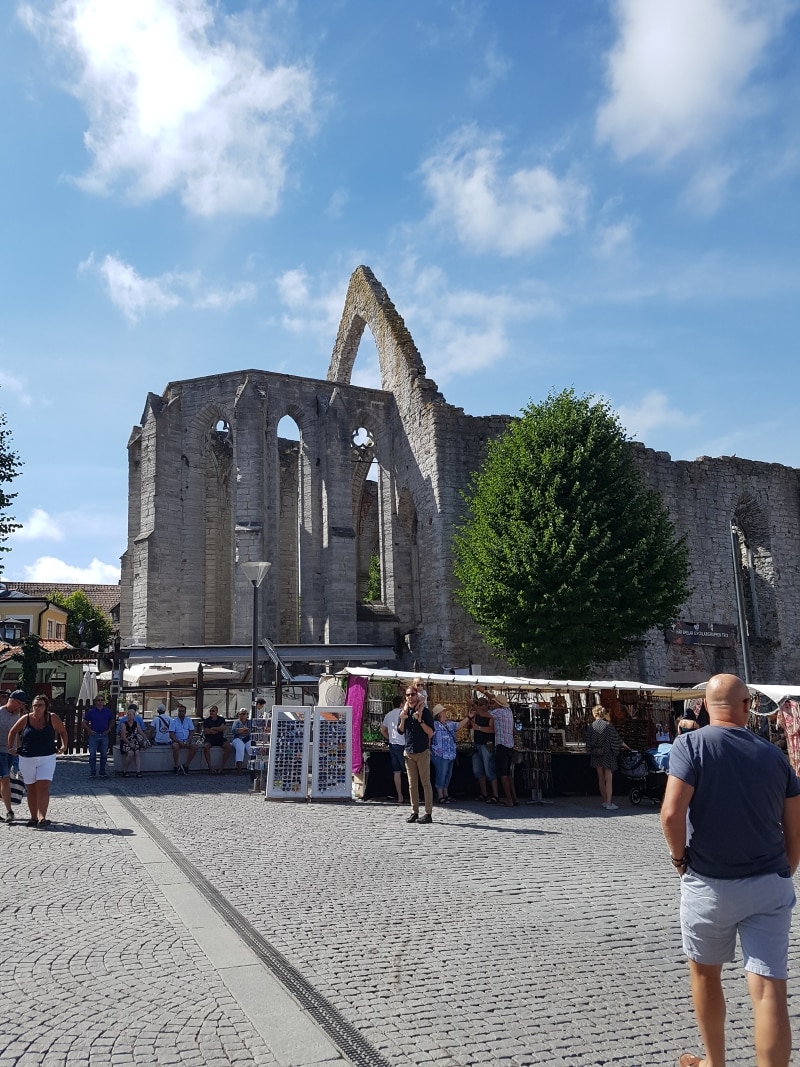 Gammal ruin på ett stort torg med marknadsstånd och människor