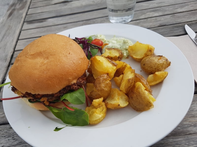 En vegoburgare i bröd med klyftpotatis, lite sallad och lite sås