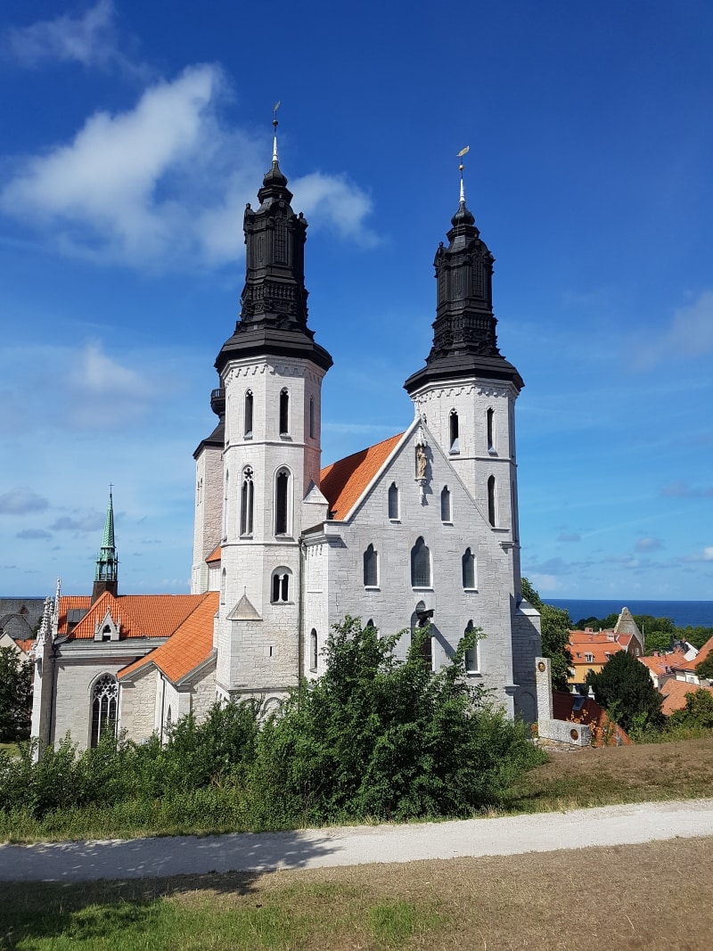 Grå kyrka med tegeltak och svarta torn