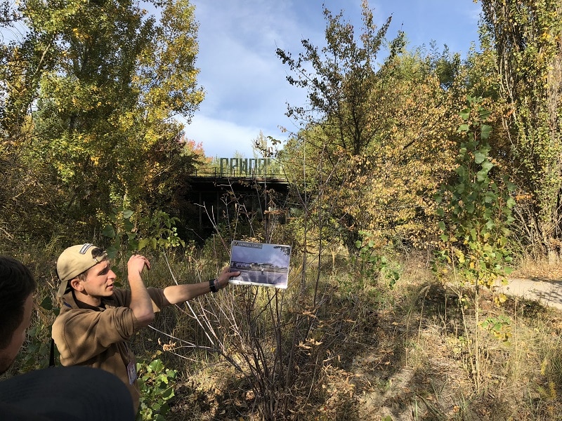 Förfallen plats med guide som visar bild på hur platsen såg ut innan