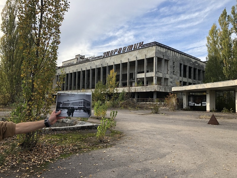 Förfallet torg och byggnad med guide som visar bild på hur platsen såg ut innan