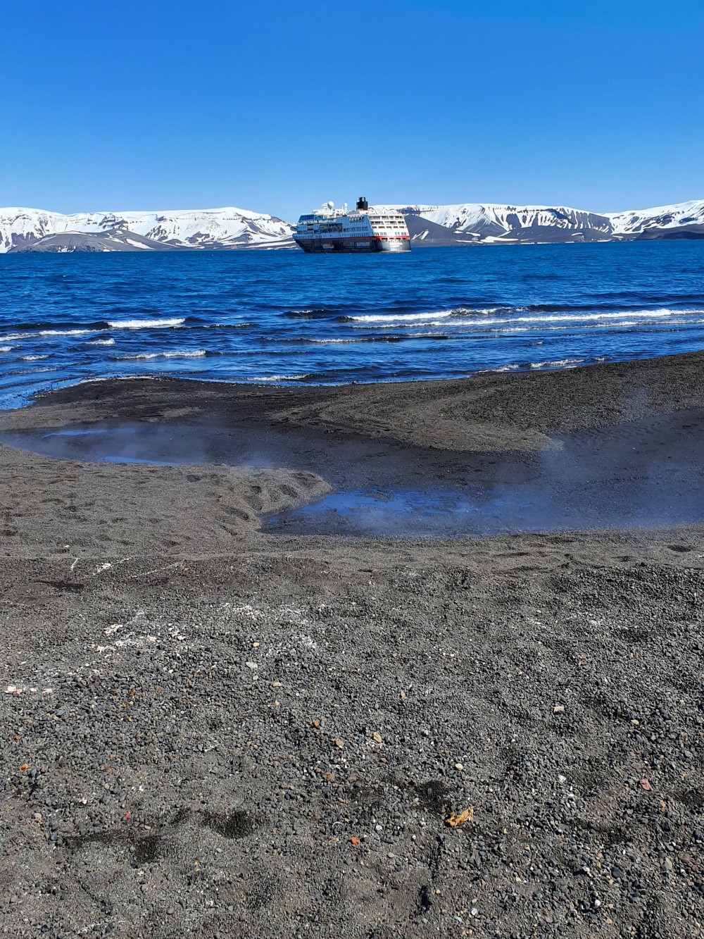 Rök från mark framför antarktiska oceanen där fartyg ankrat