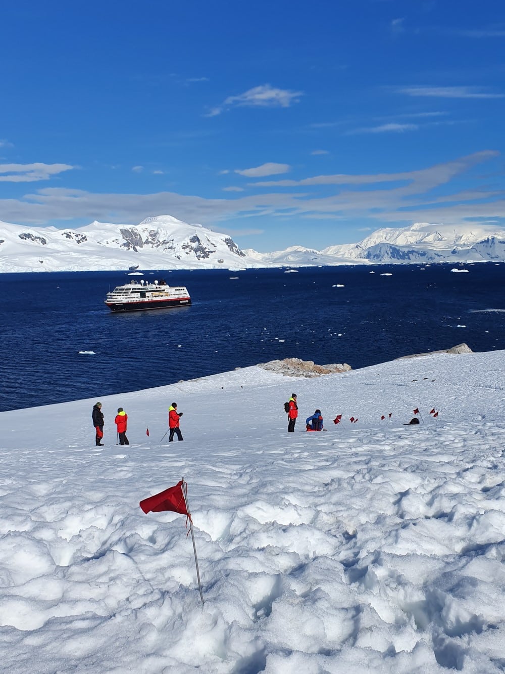 Människor i snötäckt mark bredvid antarktiska oceanen och isberg