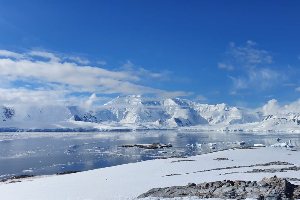 Antarktiska oceanen och moln som är lägre än snötäckta bergen