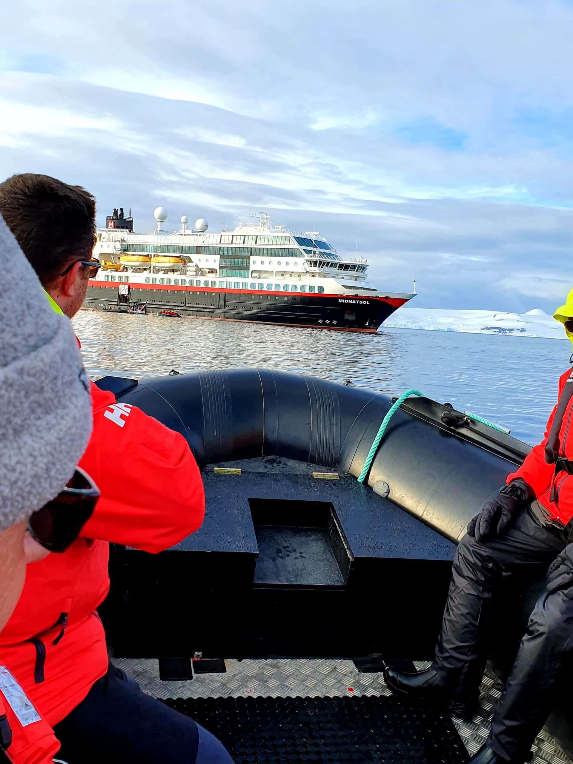 Ribbåt med människor i antarktiska oceanen mot stort fartyg