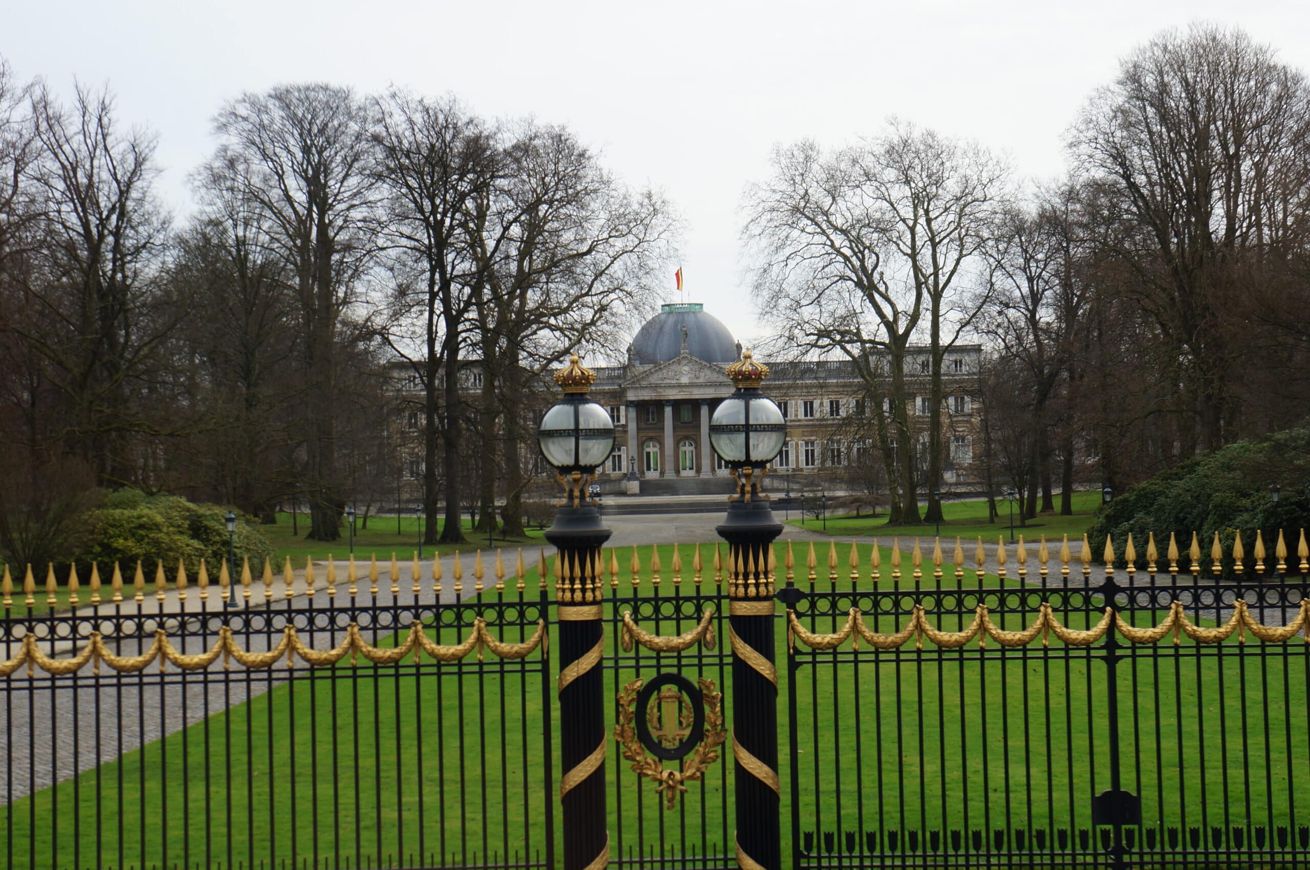 Slott med trädgård bakom vit-guldigt stängsel