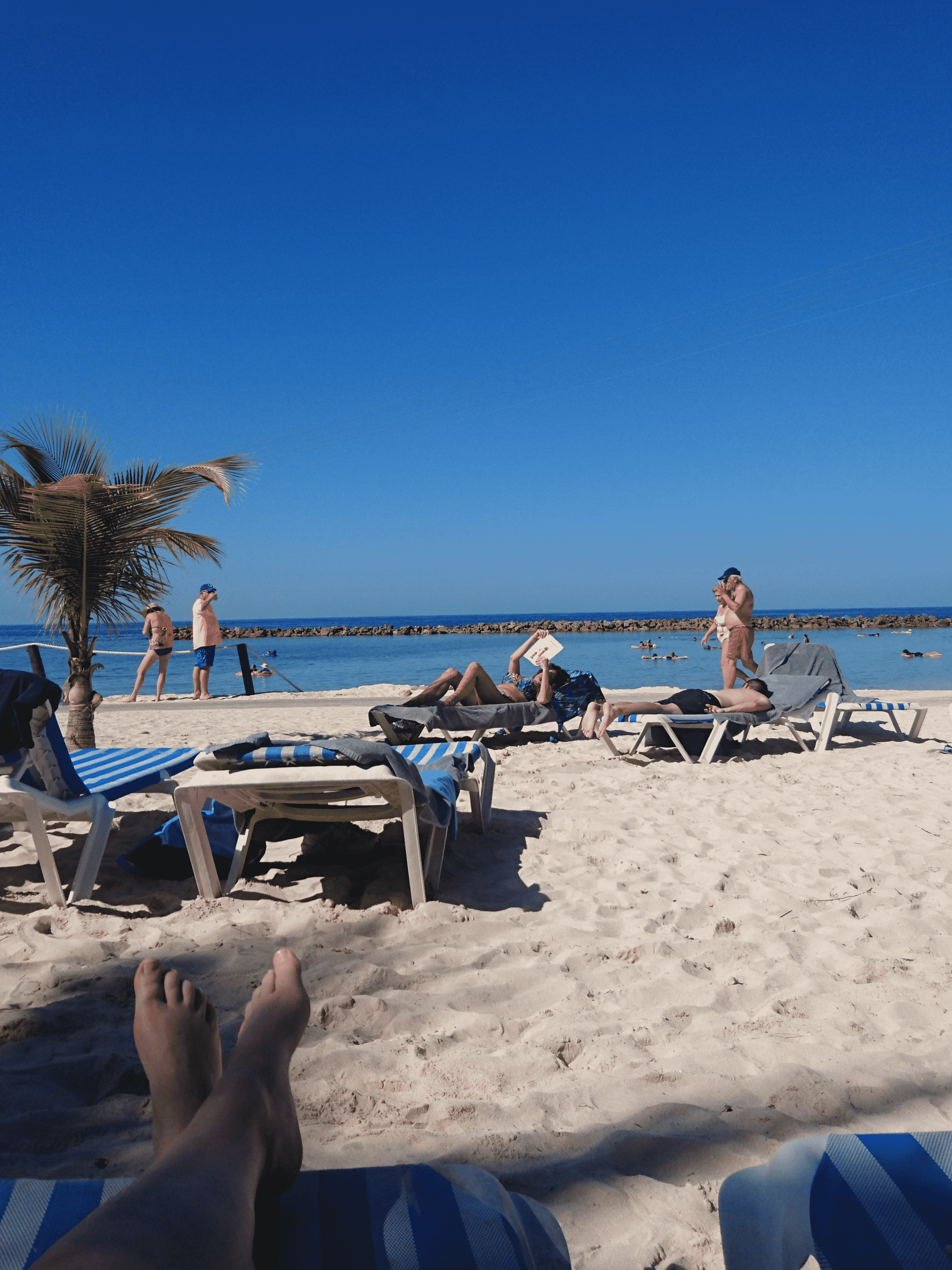 Sandstrand med solbäddar och människor vid havet