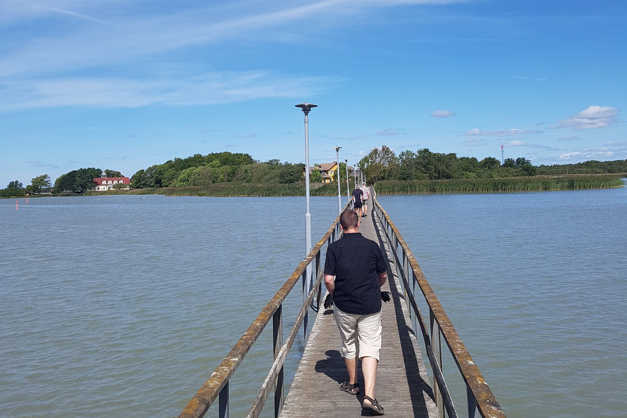 Personer promenerandes på smal bro över vattnet